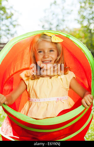 Kleines blondes Mädchen spielen und verstecken sich in Spielzeug-Rohr Stockfoto