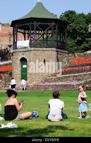 Blick auf den Schlossgarten und Musikpavillon mit der normannischen Burg auf der Rückseite mit Menschen sitzen auf dem Rasen, Tamworth. Stockfoto