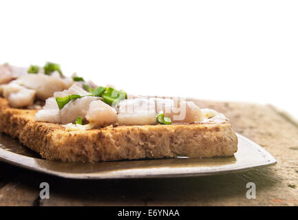 Toast mit gesalzener Hering und Zwiebel auf Metalltablett, isoliert Stockfoto