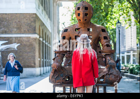 London, UK. 2. September 2014. eine Frau schaut Xavier Mascarós Installation "Hüter". Diese verrostet Eisen Krieger, fast 10 Fuß hoch, sind imposant und friedvoll und sind inspiriert von mittelalterlichen Rüstungen und alten ägyptischen und griechischen Kunst. Xavier Mascarós erste UK-Solo-Ausstellung läuft vom 3. September bis 5. Oktober in der Saatchi Gallery. Bildnachweis: Piero Cruciatti/Alamy Live-Nachrichten Stockfoto