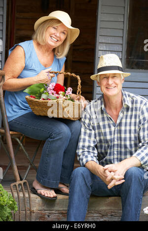 Älteres Paar, sitzen auf der Veranda mit Blumen Stockfoto