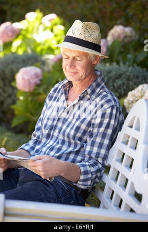 Mitte Alter Mann liest Zeitung im Garten Stockfoto