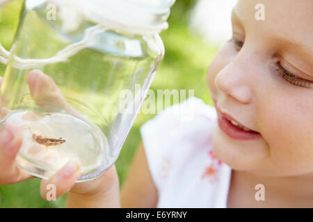 Kleines Mädchen mit Cricket in einem Glas Stockfoto