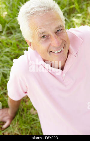 Ältere Mann sitzt auf dem Rasen Stockfoto