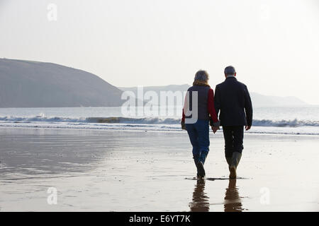 Älteres paar Winter Strand entlang spazieren Stockfoto