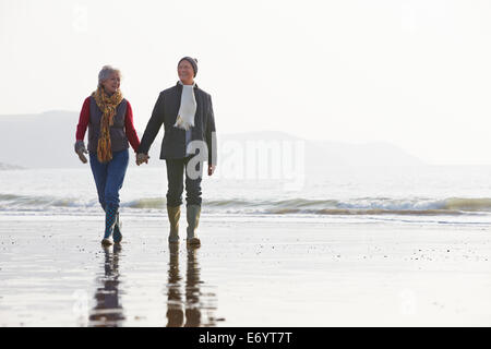 Älteres paar Winter Strand entlang spazieren Stockfoto