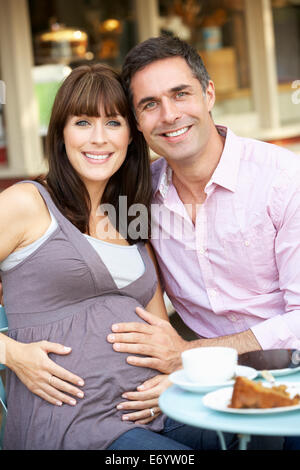 Werdende Paar sitzt vor café Stockfoto