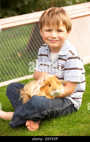 Kleiner Junge im Garten halten Meerschweinchen Stockfoto