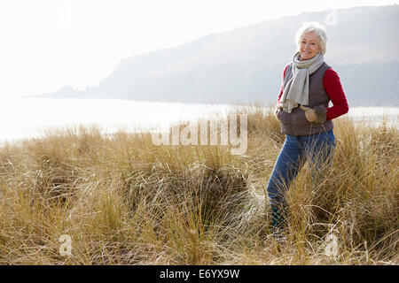 Ältere Frau Wandern durch die Sanddünen am Winter-Strand Stockfoto
