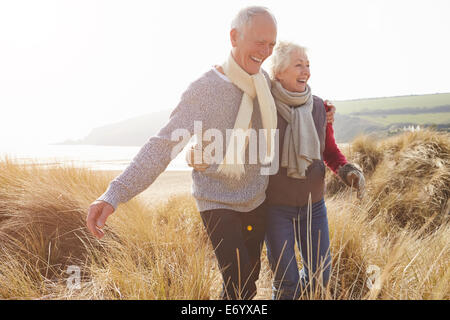 Älteres paar Wandern durch Sanddünen am Winter-Strand Stockfoto