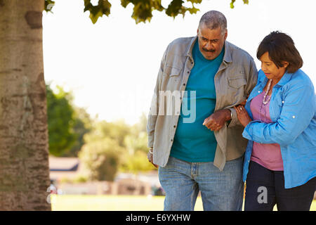 Ältere Frau Mann zu helfen, als sie zusammen im Park Fuß Stockfoto