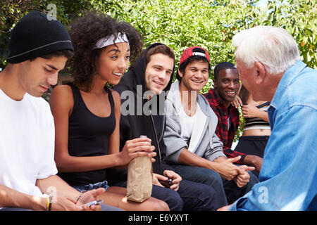 Ältere Mann im Gespräch mit Bande von Jugendlichen Stockfoto