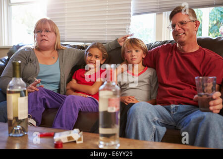Eltern sitzen mit Kindern, Rauchen und trinken auf Sofa. Stockfoto