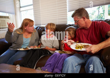 Familie mit schlechte Ernährung sitzen auf Sofa Essen Mahlzeit und streiten Stockfoto