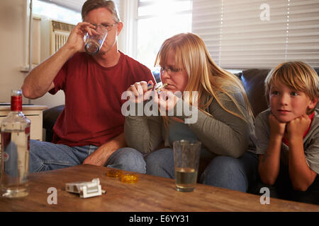 Eltern mit Kindern auf Sofa sitzen Drogen und trinken Stockfoto