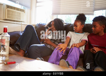Mutter sitzt auf dem Sofa mit Kindern Rauchen und trinken Stockfoto