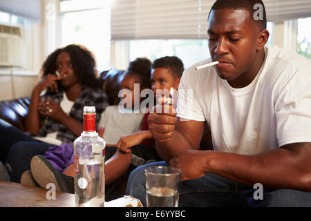Eltern sitzen mit Kindern, Rauchen und trinken auf Sofa. Stockfoto