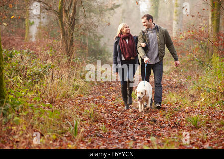 Paar Spaziergang mit Hund durch den Wald Winter Stockfoto