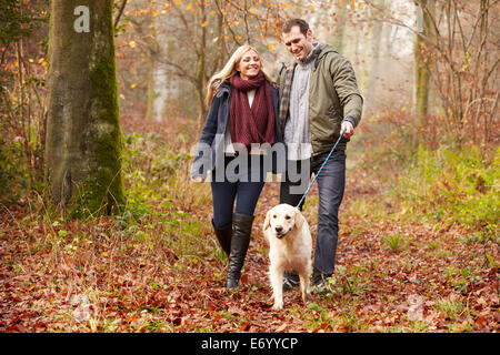 Paar Spaziergang mit Hund durch den Wald Winter Stockfoto