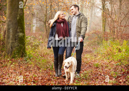 Paar Spaziergang mit Hund durch den Wald Winter Stockfoto