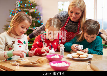 Mutter und Kinder dekorieren Weihnachtsplätzchen zusammen Stockfoto