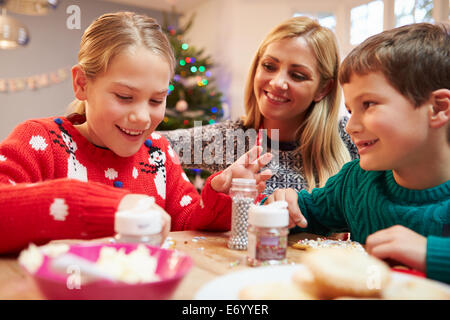 Mutter und Kinder dekorieren Weihnachtsplätzchen zusammen Stockfoto