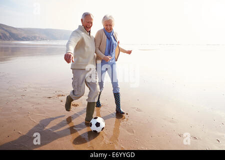 Älteres paar Fußballspielen am Winter-Strand Stockfoto