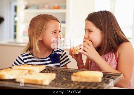 Zwei Mädchen essen Käse auf Toast In Küche Stockfoto