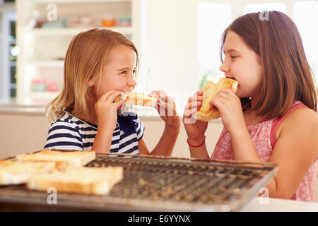 Zwei Mädchen essen Käse auf Toast In Küche Stockfoto