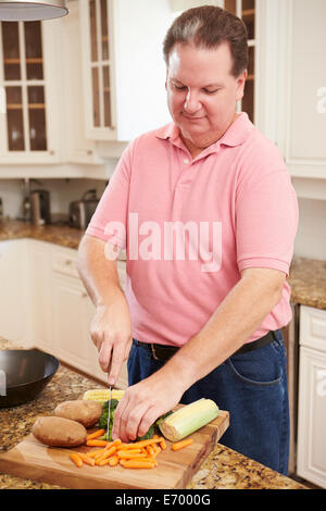 Übergewichtiger Mann vorbereiten Gemüse in der Küche Stockfoto