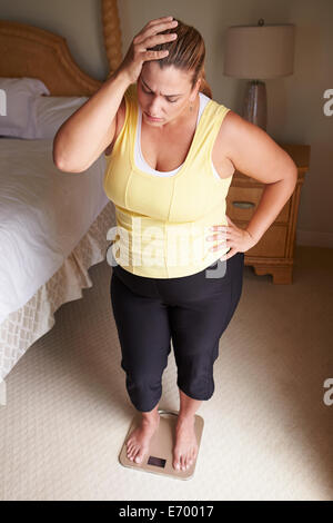 Übergewichtige Frau wiegen sich auf Skalen im Schlafzimmer Stockfoto