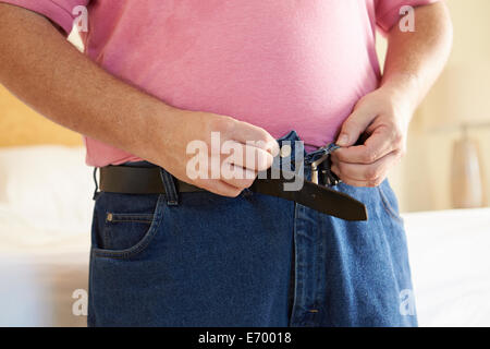 Nahaufnahme von übergewichtigen Mann, der versucht, Hose zu befestigen Stockfoto