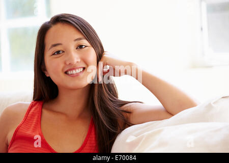 Porträt der Asiatin, die entspannend auf Sofa