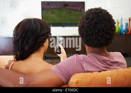 Rückansicht des Paares auf Sofa vor dem Fernseher zusammen sitzen Stockfoto