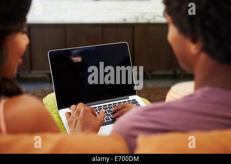 Rückansicht des Paares auf Sofa mit Laptop Stockfoto