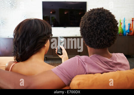 Rückansicht des Paares auf Sofa vor dem Fernseher zusammen sitzen Stockfoto