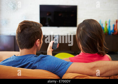 Rückansicht des Paares auf Sofa vor dem Fernseher zusammen sitzen Stockfoto