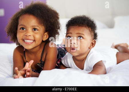 Schwester mit Bruder liegend im Bett der Eltern Stockfoto