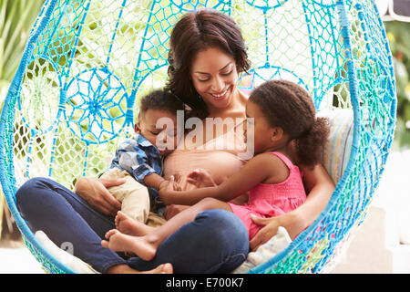 Mutter mit Kindern entspannend auf Garten-Schaukelsitz Stockfoto