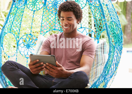 Mann im Garten Schaukelsitz mit Digital-Tablette Stockfoto