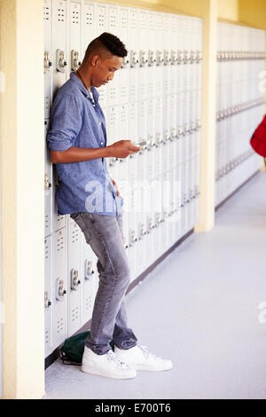 Männlich-Gymnasiast durch Schließfächer mit Mobiltelefon Stockfoto