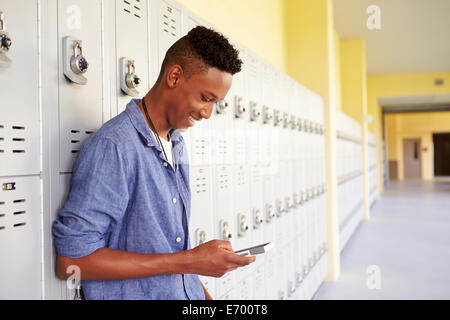 Männlich-Gymnasiast durch Schließfächer mit Mobiltelefon Stockfoto