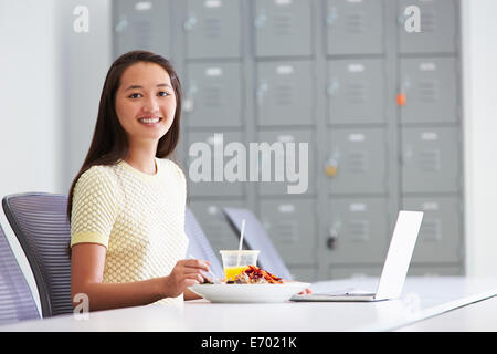 Frau arbeitet im Design-Studio mit Mittagessen am Schreibtisch Stockfoto