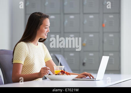 Frau arbeitet im Design-Studio mit Mittagessen am Schreibtisch Stockfoto