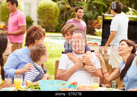 Multi-Generationen-Familie gemeinsame Mahlzeit im Garten genießen