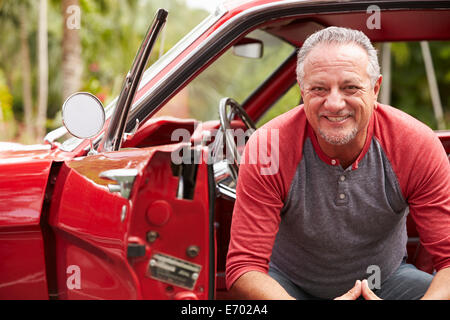 Ehemaliger Senior Mann sitzt im restaurierten Oldtimer Stockfoto