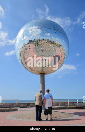 Zwei Leute, die auf der Suche an der rotierenden riesige Spiegel Kugel auf der South Shore Promenade von Blackpool, Lancashire, Großbritannien Stockfoto