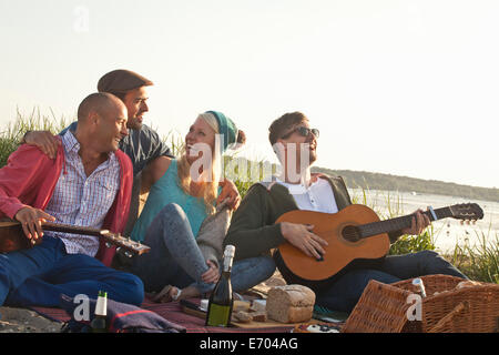 Vier Erwachsene Freunde, die mit einer Party am Strand von Bournemouth, Dorset, Großbritannien Stockfoto