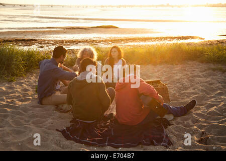 Fünf Erwachsene Freunde picknicken bei Sonnenuntergang am Strand von Bournemouth, Dorset, Großbritannien Stockfoto