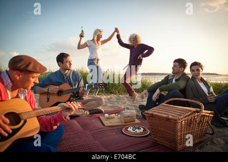 Sechs Erwachsene Freunde feiern und tanzen am Strand von Bournemouth, Dorset, Großbritannien Stockfoto